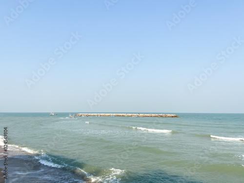 View of waves barrier in the sea with ocean waves against clear blue sky with copy space.