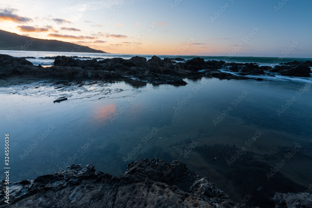 sunset over the sea at ninety mile beach in ahipara new zealand sunset over the sea at ninety mile beach in ahipara new zealand