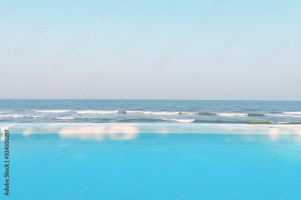 Fresh cool blue pool and ocean waves with infinite view of clear sky background with ray of sunshine, with copy space.