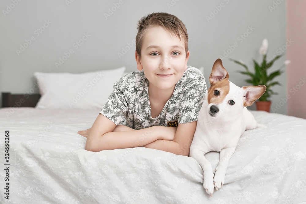 Two friends boy and dog lying together on bed. Boy on bed with dog jack russell terrier. Friendship concept. Cute little boy with funny dog on bed at home. Young Boy Hugging his Dog. Two friends boy and dog lying together on bed. Boy on bed with dog jack russell terrier. Friendship concept. Cute little boy with funny dog on bed at home. Young Boy Hugging his Dog.