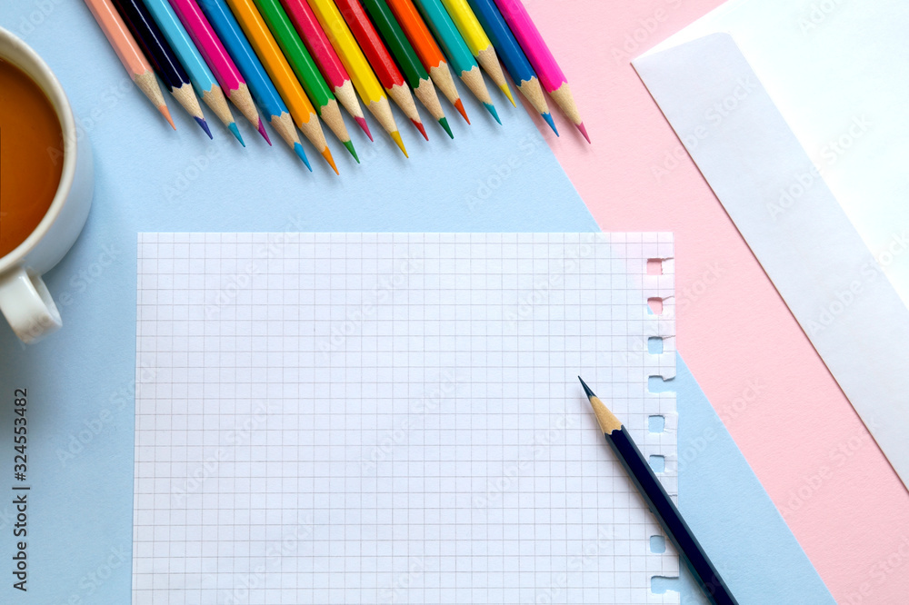 Top view of a sheet of paper, colored pencils, an envelope and a Cup of tea on the table. Write a letter. Top view of a sheet of paper, colored pencils, an envelope and a Cup of tea on the table. Write a letter.