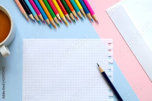 Top view of a sheet of paper, colored pencils, an envelope and a Cup of tea on the table. Write a letter. 