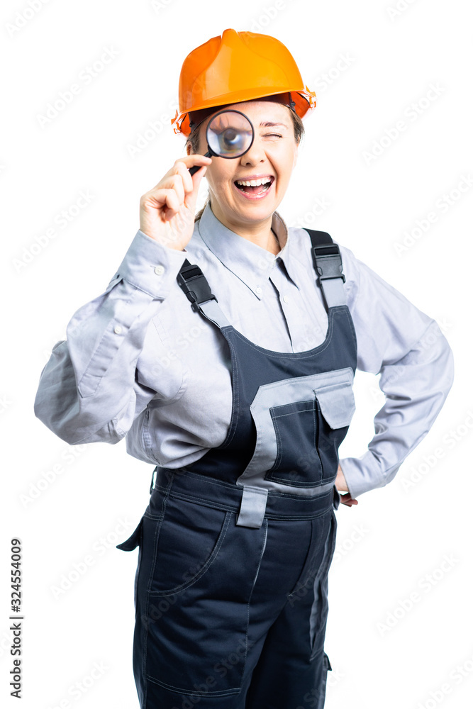 girl construction engineer examines something in a magnifying glass. Isolated girl construction engineer examines something in a magnifying glass. Isolated