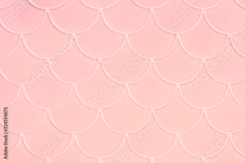 Lihgt pink ceramic tiles in the form of scales. Mosaic Tiles on the wall