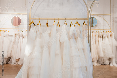 Foto a lot of beautiful white wedding dresses on hangers in the store
