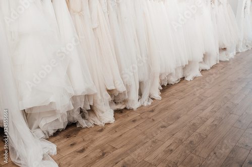 a lot of beautiful white wedding dresses on hangers in the store