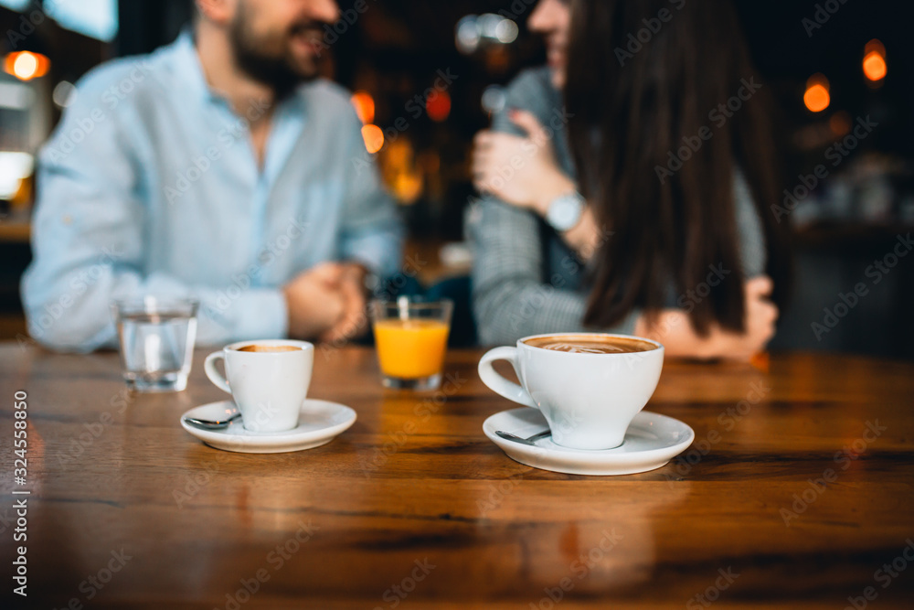 close up of coffee in mug in cafeteria. romantic couple talking in blurred background close up of coffee in mug in cafeteria. romantic couple talking in blurred background
