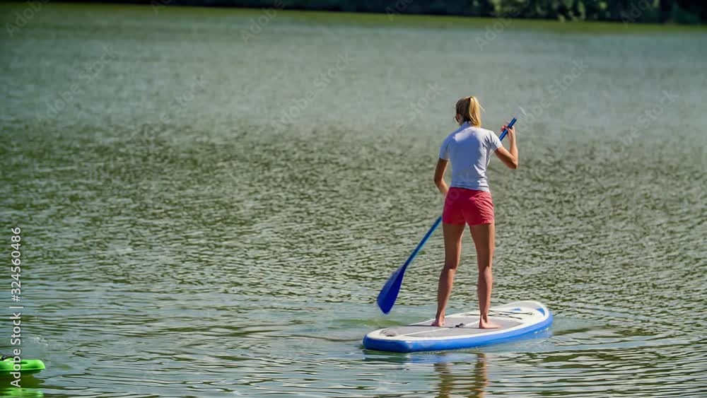 Adult Female Standing Up On Paddle Board On Lake. Slow Motion Adult Female Standing Up On Paddle Board On Lake. Slow Motion