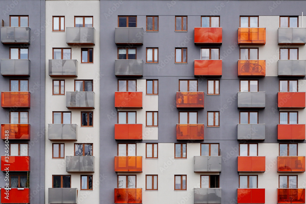 Modern, comfortable apartment house with bright orange balconies, the view from street.