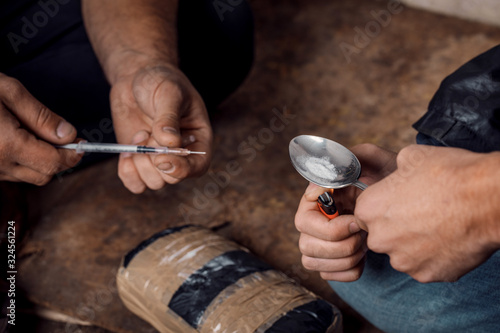 two shabby  men preparing drug injection in slums photo