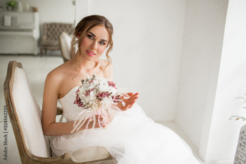 Young bride in a beautiful dress holding a bouquet of flowers in bright white studio. Wedding concept. Young bride in a beautiful dress holding a bouquet of flowers in bright white studio. Wedding concept.