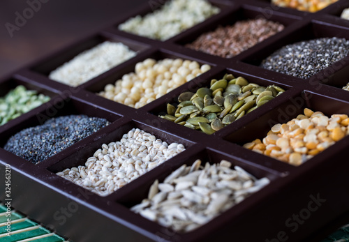 A close up angled view of a wooden box filled with sections of seeds and grains.