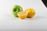 Whole and half lemon on white background with a green apple