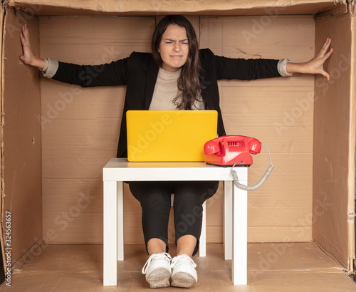 Принти на полотні beautiful businesswoman sits in a tight paper office, needs more space, pushes t