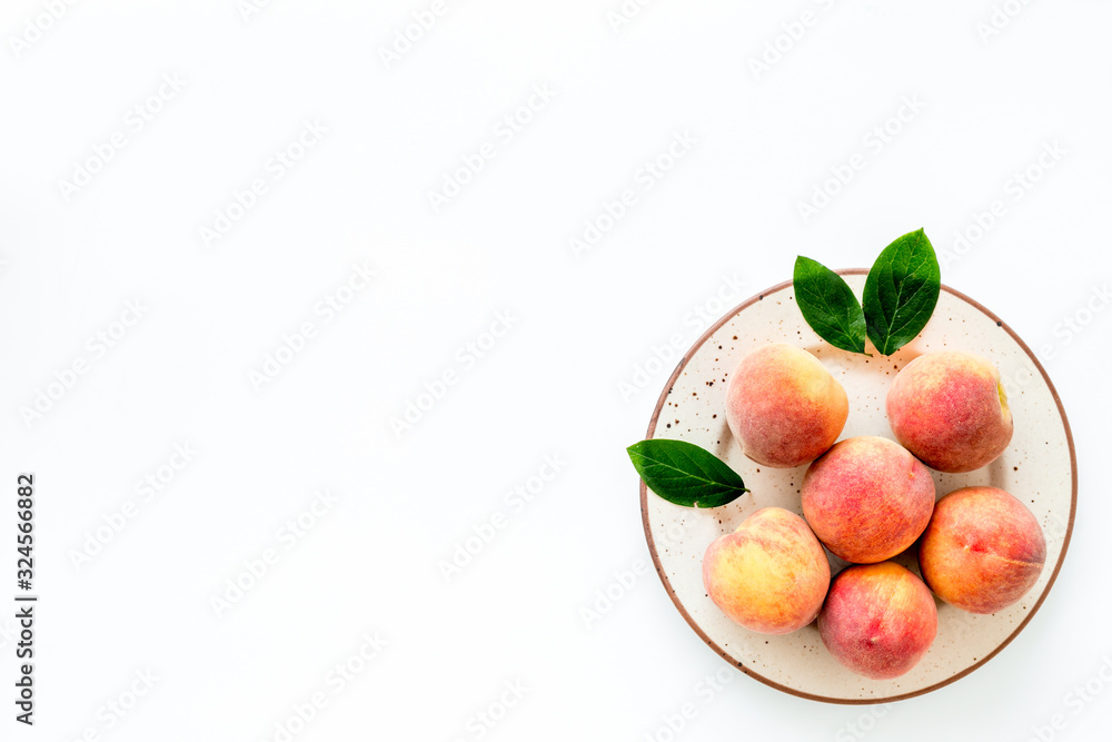 Summer fruits. Ripe red peaches on plate on white table top-down copy space Summer fruits. Ripe red peaches on plate on white table top-down copy space