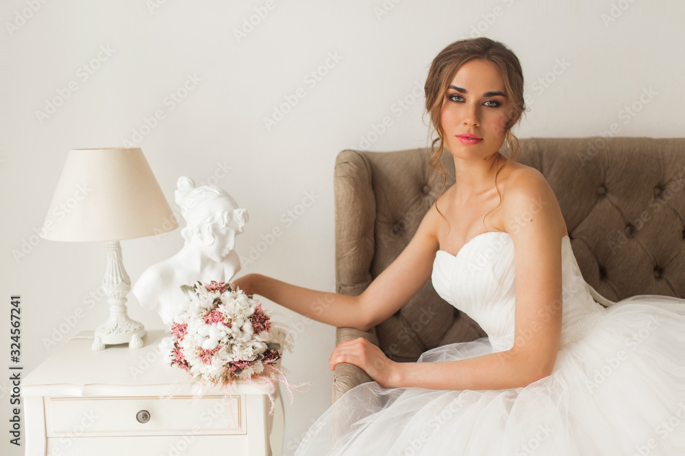 Young bride in a beautiful dress sitting at home with nice white interior. Wedding concept. Young bride in a beautiful dress sitting at home with nice white interior. Wedding concept.