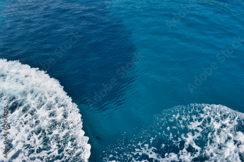 smooth surface of blue sea water with foaming bubbles of waves