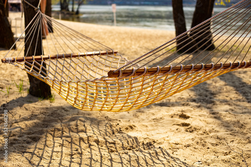 Traditional wattled  hammock with wooden planks hanging between the treas on the sandy beach beautiful sunny aspring (or summer) day