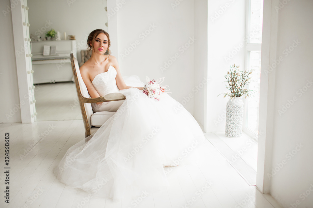 Young bride in a luxury dress holding a bouquet of flowers in bright white studio. Wedding fashion concept. Young bride in a luxury dress holding a bouquet of flowers in bright white studio. Wedding fashion concept.
