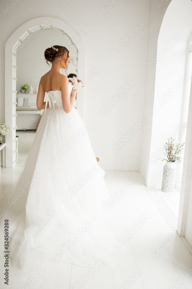 Young bride in a luxury dress holding a bouquet of flowers in bright white studio. Wedding fashion concept. Young bride in a luxury dress holding a bouquet of flowers in bright white studio. Wedding fashion concept.