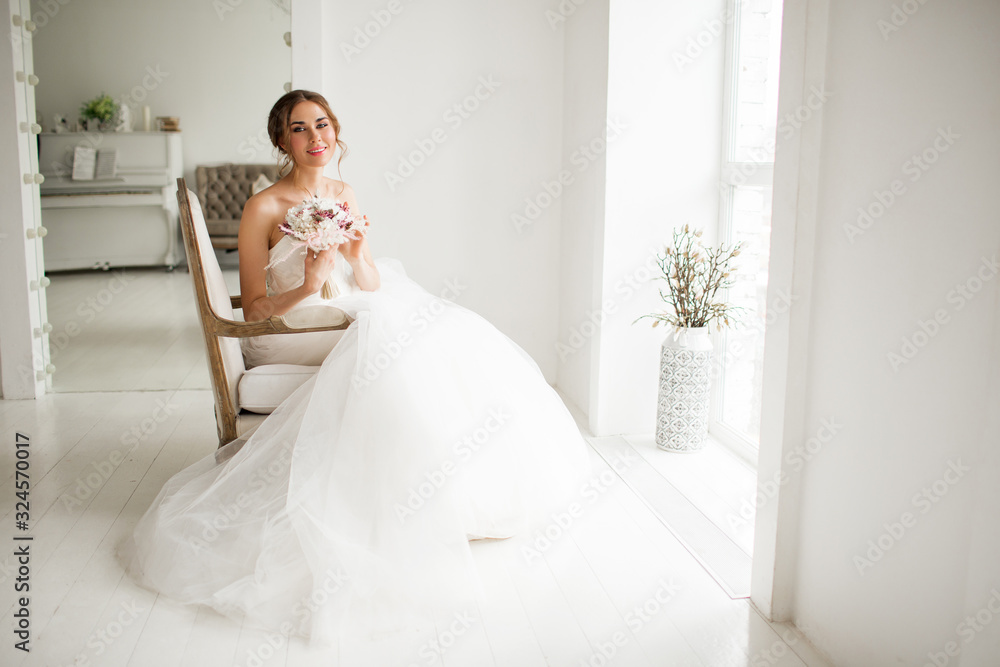 Young bride in a luxury dress holding a bouquet of flowers in bright white studio. Wedding fashion concept. Young bride in a luxury dress holding a bouquet of flowers in bright white studio. Wedding fashion concept.