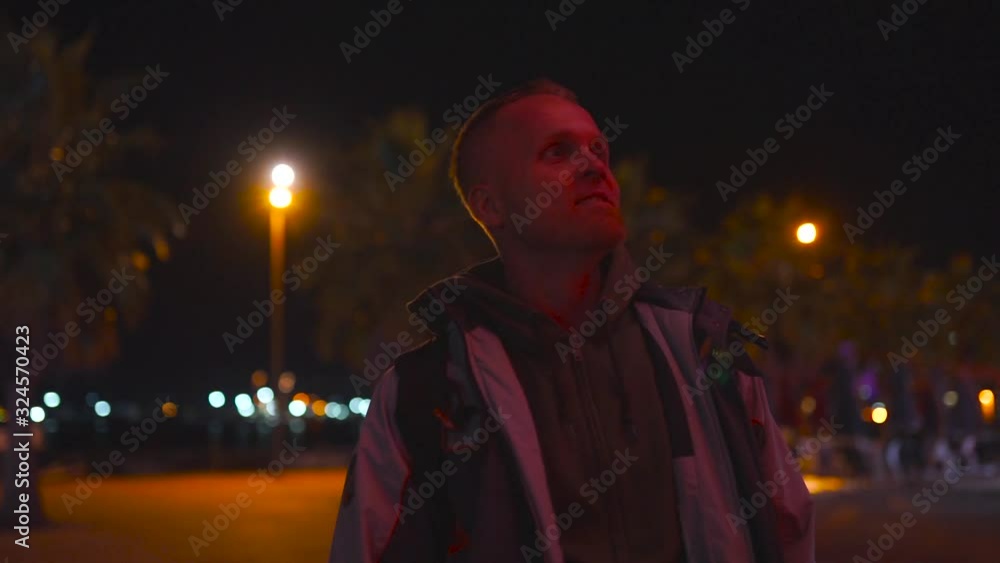 Handsome man looking at the camera and smiling at night with red lighting on a background of a ferris wheel in Batumi, Georgia Handsome man looking at the camera and smiling at night with red lighting on a background of a ferris wheel in Batumi, Georgia