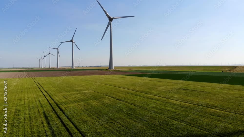 Aerial view of windmills station with rotating propellers generating alternative clean green power from eco resources in rural agri environment.Birds eye view of line of turbines producing electricity Aerial view of windmills station with rotating propellers generating alternative clean green power from eco resources in rural agri environment.Birds eye view of line of turbines producing electricity