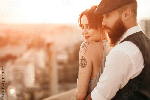 Happy affectionate couple standing on rooftop and enjoying cityscape