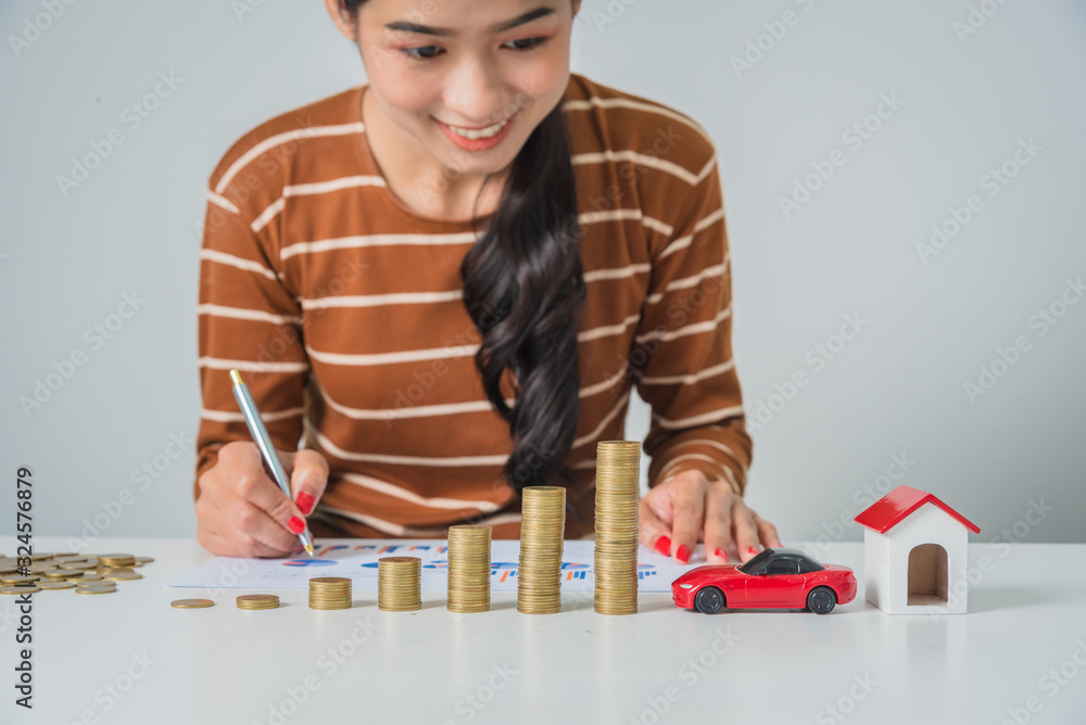 Young business woman looking at stack of coins, hand holding pen to analysis finance chart for home and car expense. Young business woman looking at stack of coins, hand holding pen to analysis finance chart for home and car expense.