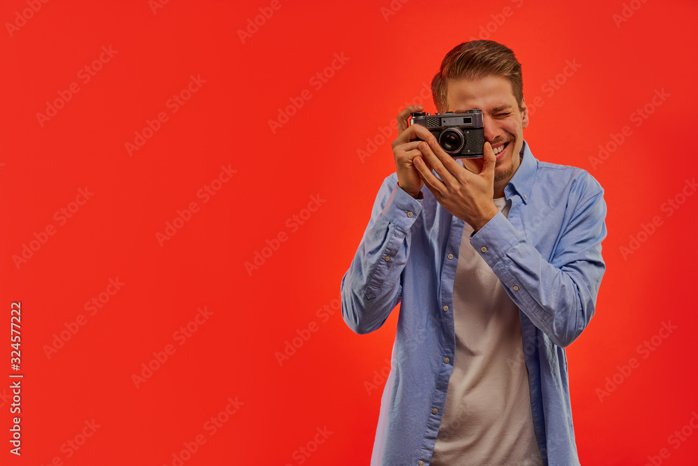 Smiling man with a beard in a blue shirt takes a photo on old photo camera. Smiling man with a beard in a blue shirt takes a photo on old photo camera.