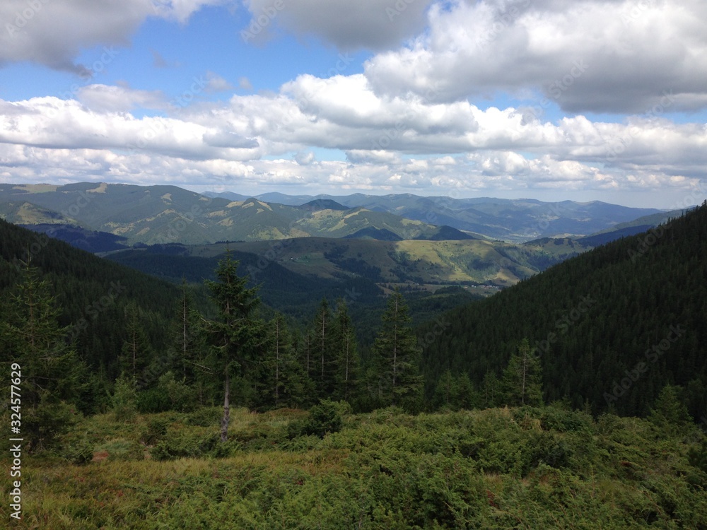 The tops of the mountains against the cloudy sky, view into the distance. Summer, mountain landscape in the Carpathians. Hills and mountain ranges among nature