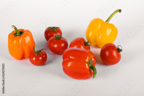 Red tomatoes and peppers on a white background with shadows. top view