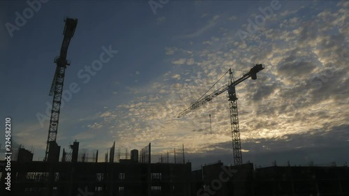 4k 30 fps time-lapse silhouettes of two tower construction cranes at dawn