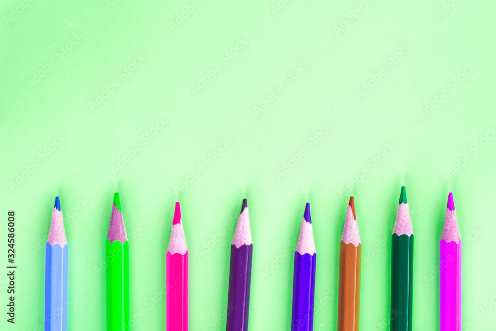 Colored pencils on a bright light green background. The concept of children's creativity. Colored pencils on a bright light green background. The concept of children's creativity.