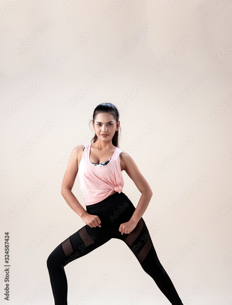 Young lady wearing exercise set twisted her body and face,fist down in front of her leg,show basic of dance workout,with happy feeling