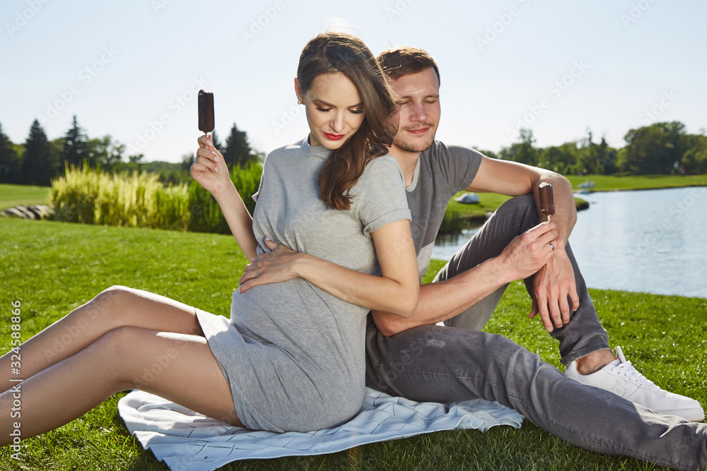 Happy couple in love waiting for child pregnancy hug summer green trees sitting on the grass rest nature husband wife baby family parent, man woman romantic dating harmony relationship ice-cream lake. Happy couple in love waiting for child pregnancy hug summer green trees sitting on the grass rest nature husband wife baby family parent, man woman romantic dating harmony relationship ice-cream lake.