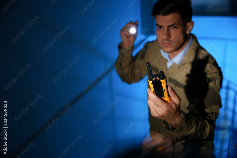 Professional security guard with portable radio set in dark room, focus on hand Professional security guard with portable radio set in dark room, focus on hand