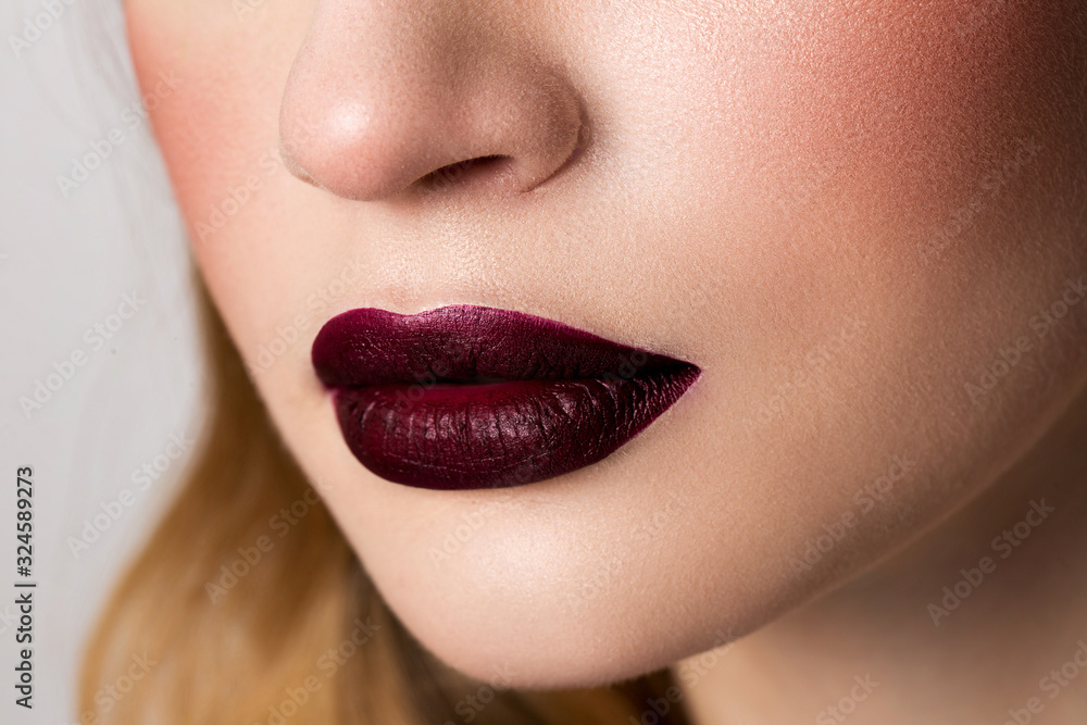 Fototapeta premium Girl's lips with matte lipstick burgundy color.