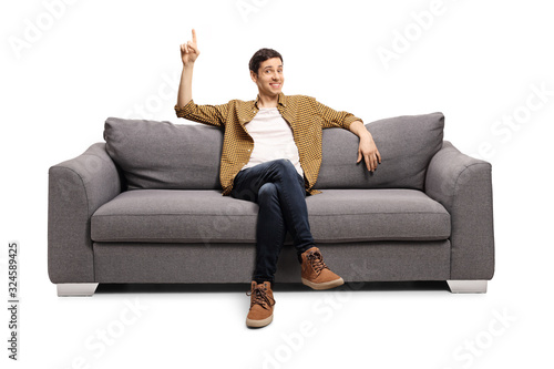 Young man sitting on a sofa and pointing up