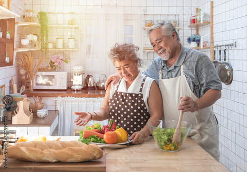 Photography Senior couple having fun in kitchen with healthy food - Retired people cooking meal at home with man and woman preparing lunch with bio vegetables - Happy elderly concept with mature funny pensioner