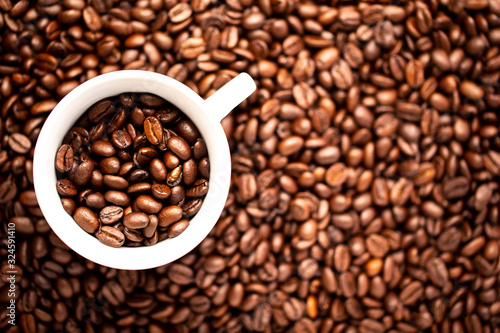 White cup with coffee beans on a background of coffee beans