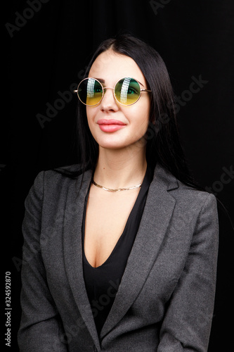 Wallpaper Mural Image of sweet confident young lady standing over black background in studio, wearing white casual jacket and fashionable round green eyeglasses, having long dark hair. Youth concept Torontodigital.ca