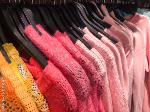 Lots of pink sweaters and a couple of yellow ones on hangers in the store