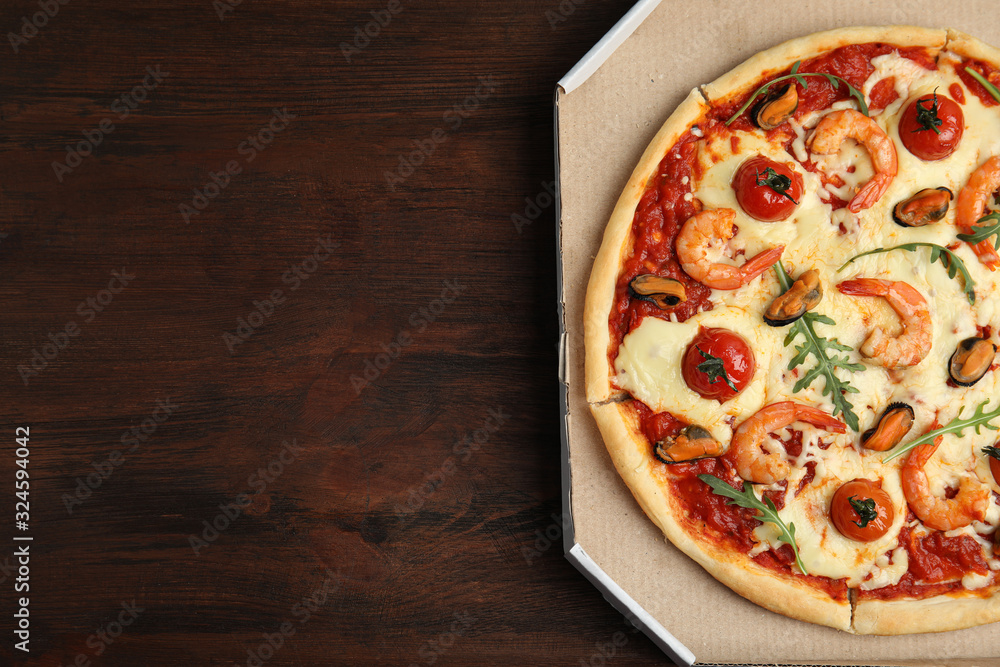 Delicious seafood pizza in cardboard on wooden table, top view. Space for text