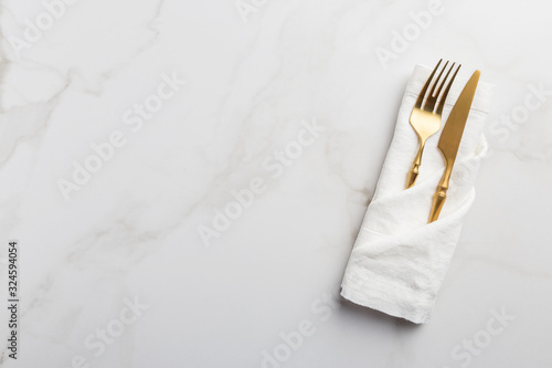 Tableware at white napkin on white marble background