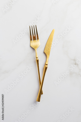 Flatware on white background. Gold Fork and knife at white marble background