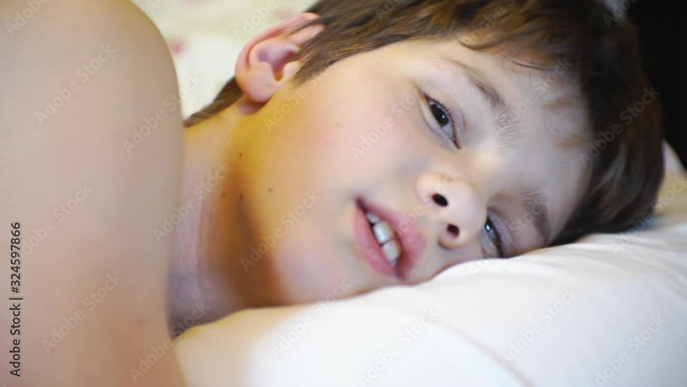 cute boy of school age, lies in bed and smiling.closeup cute boy of school age, lies in bed and smiling.closeup