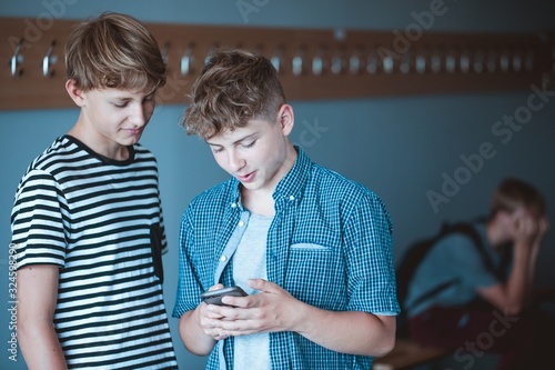 Two teenage boys checking something on the mobile phone at school photo