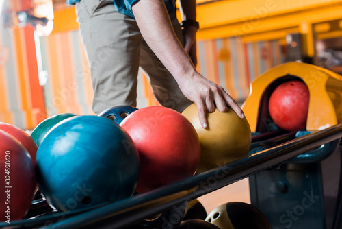 partial view of man choosing bowling ball in bowling club