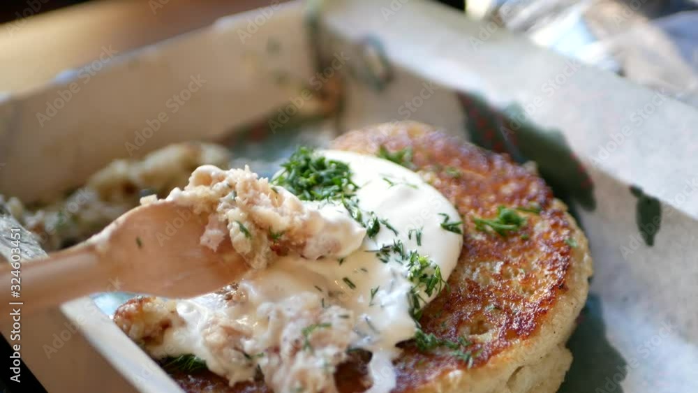 Potato pancake with sour cream. Decorated with greenery. Close-up. There is an eco dish dish Potato pancake with sour cream. Decorated with greenery. Close-up. There is an eco dish dish
